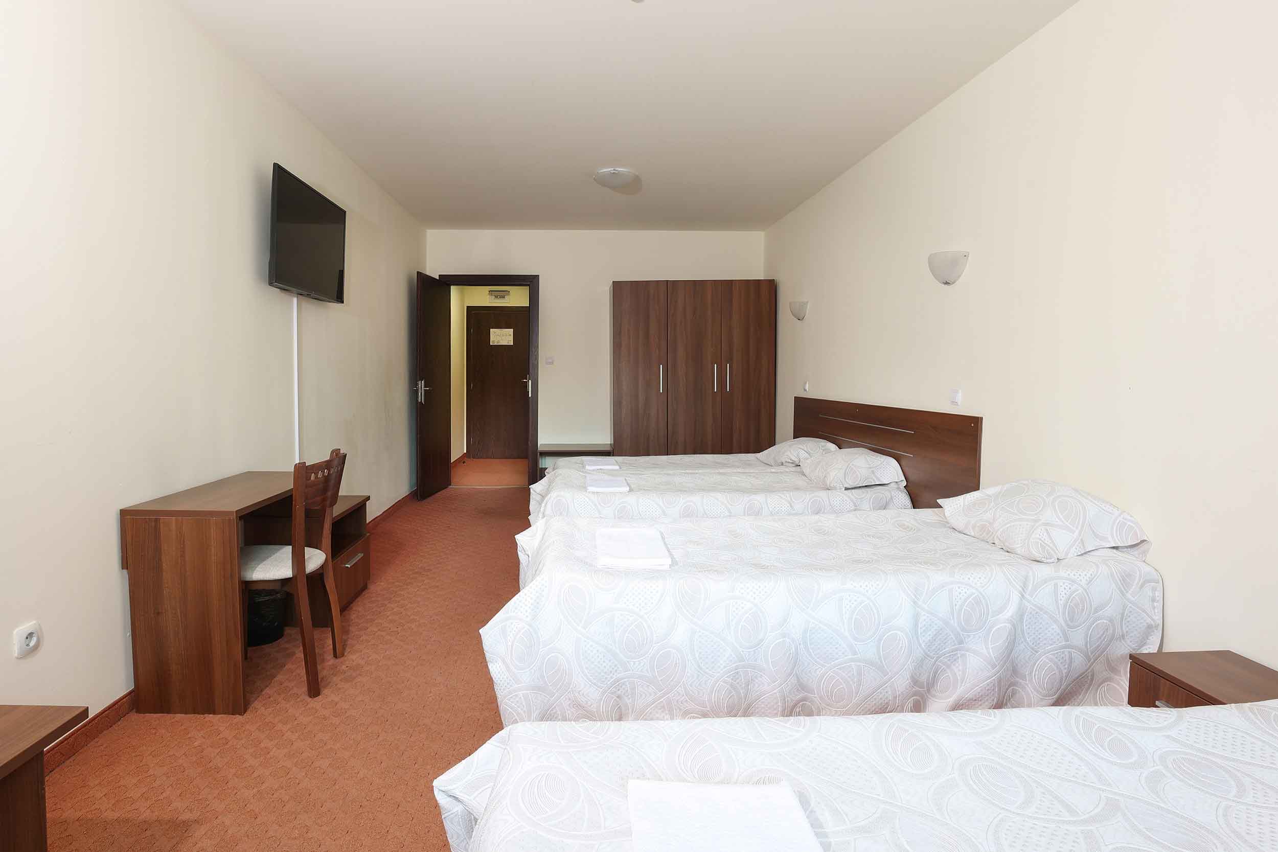 Quadruple room at Kartala hotel. In the picture there are one king size bed and two single beds. One desk, one chair, one cabinet and tv on the wall